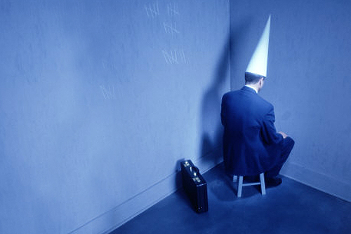 businessman-sitting-in-corner-with-dunce-hat.jpg